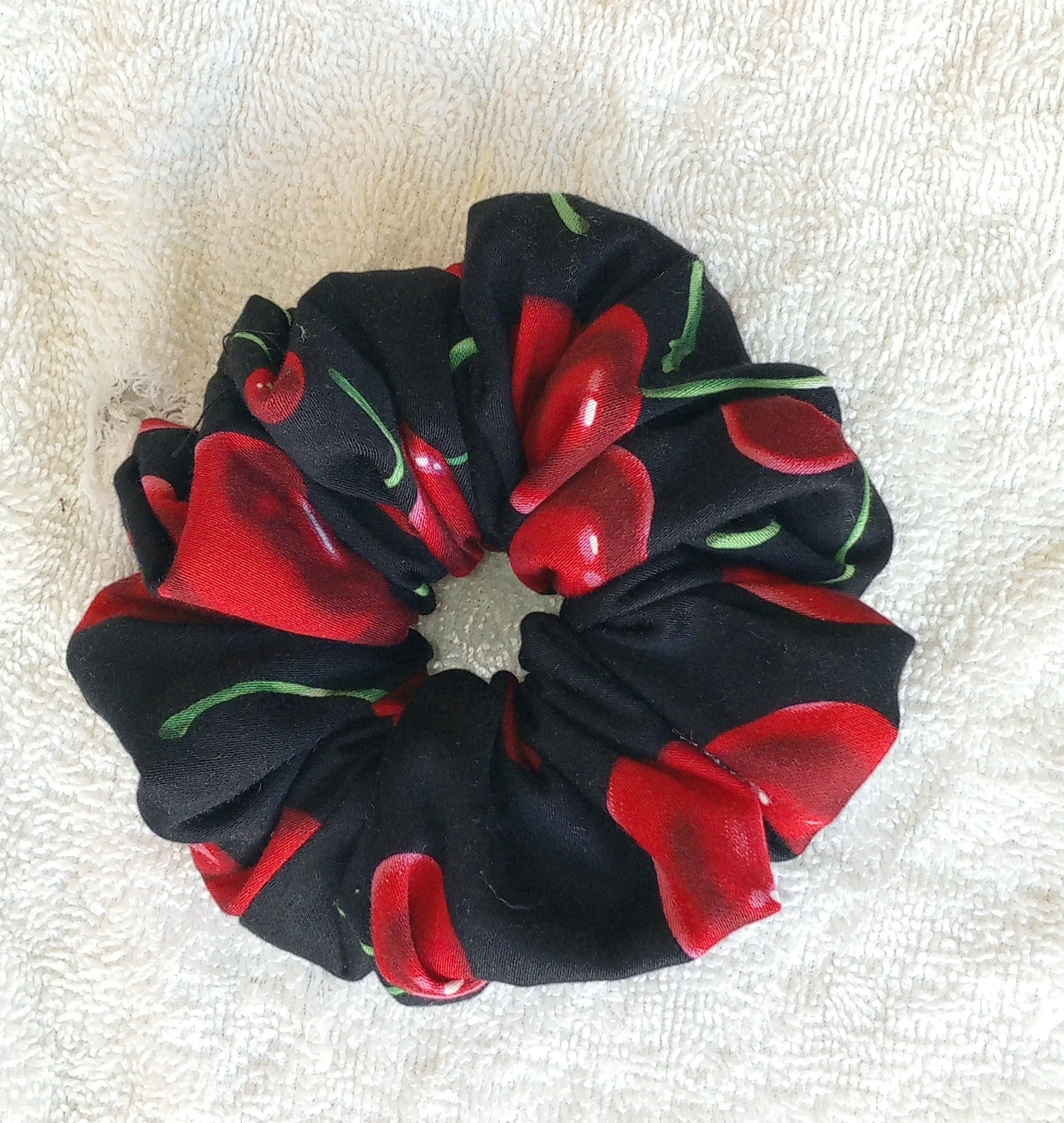 Black scrunchie with red and green floral pattern on a white background
