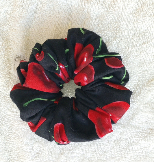 Black scrunchie with red and green floral pattern on a white background